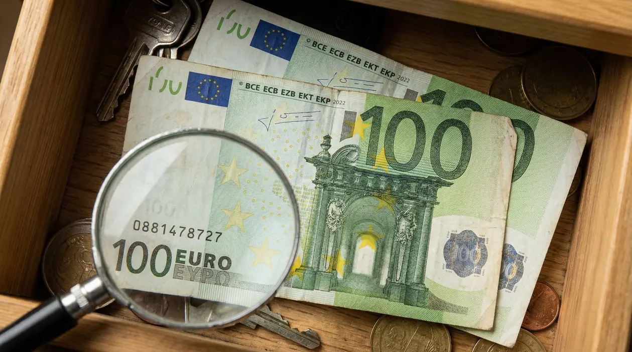 Banconote da 100 euro osservate con lente d'ingrandimento in un cassetto