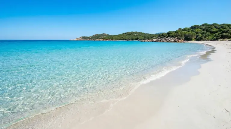 Spiaggia con sabbia bianca e mare cristallino in una baia tranquilla e incontaminata.